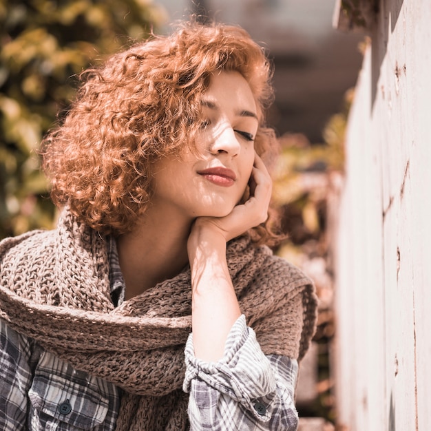 Free photo smiling woman near wall holding face