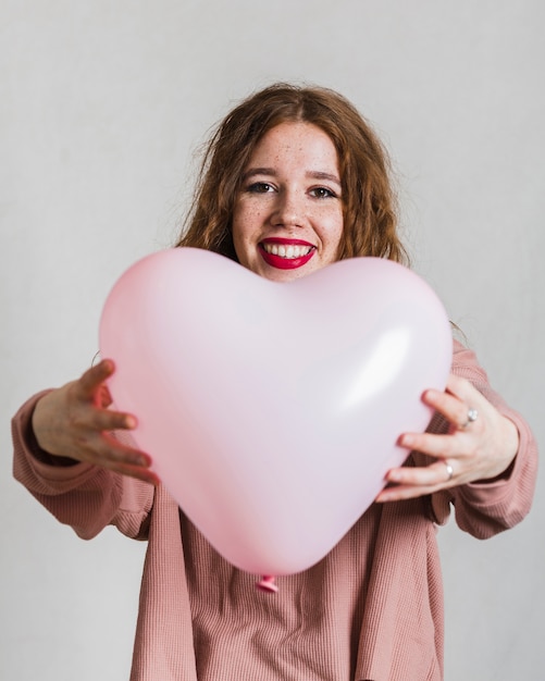 Free photo smiling woman offering a balloon