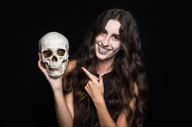 Smiling woman pointing at skull