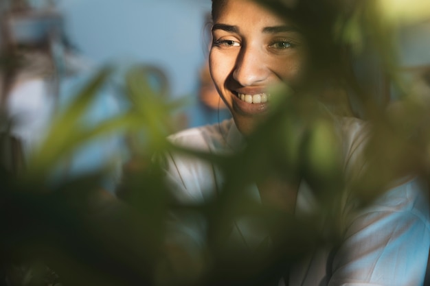 Free photo smiling woman portrait  with blurred plant