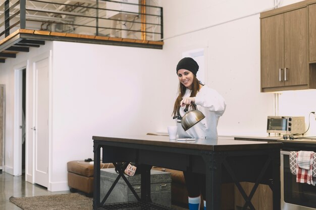 Smiling woman pouring hot water into mug