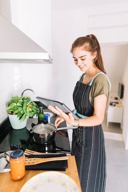 Free photo smiling woman preparing food holding digital tablet