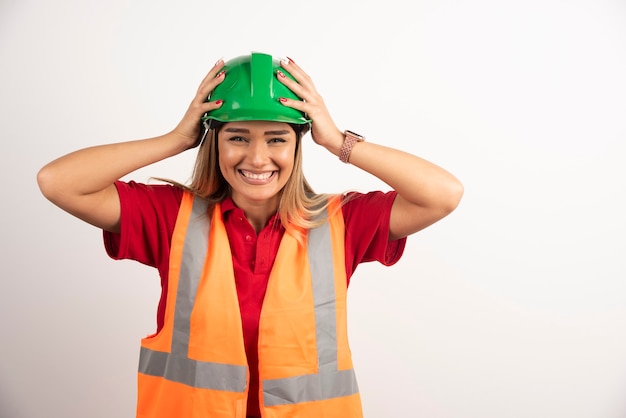 Smiling woman in protective uniform and helmet posing on white background.