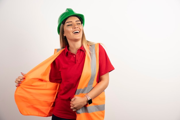 Smiling woman in protective uniform and helmet posing on white background.