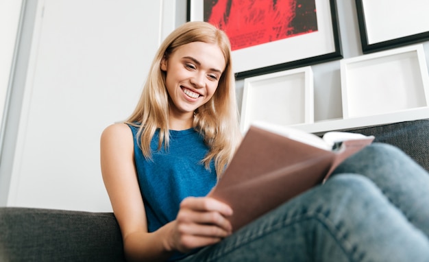 Smiling woman resting and reading book at home