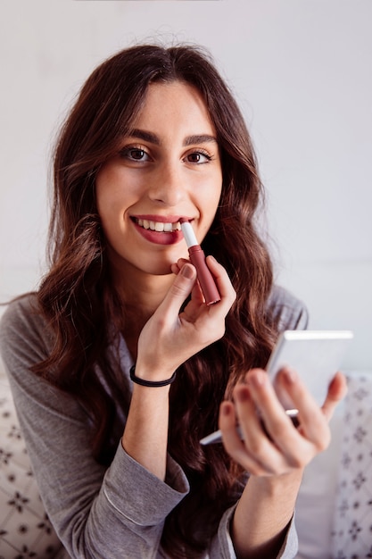 Smiling woman rouging lips