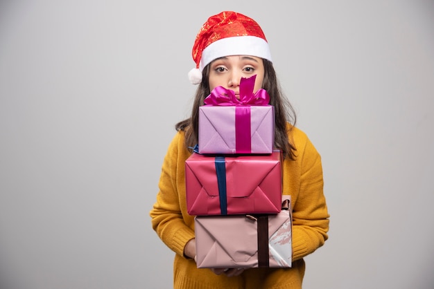 Smiling woman in Santa hat holding gift boxes. 