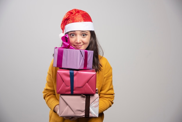 Smiling woman in Santa hat holding gift boxes. 