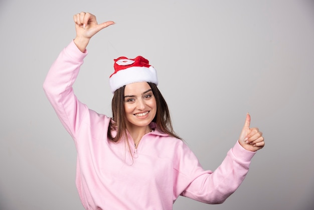 Smiling woman in Santa's hat showing thumbs up.