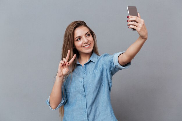 Smiling Woman in shirt making selfie on smartphone