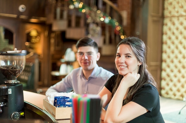 Smiling woman sitting at bar counter near man