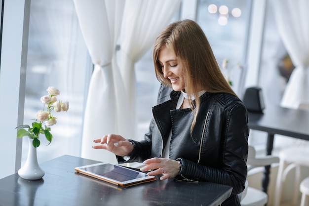 Free Photo smiling woman sitting at a restaurant touching a tablet