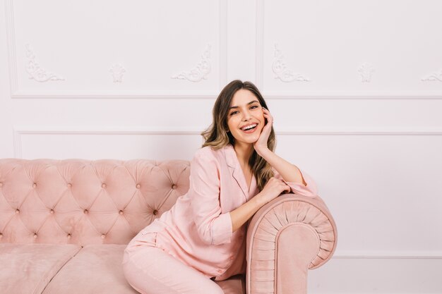 Smiling woman sitting on sofa and propping face with hand