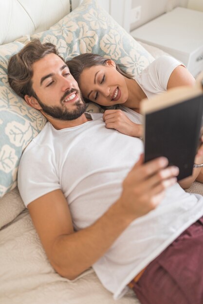 Smiling woman sleeping near reading man