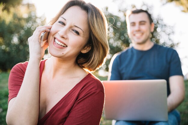 Smiling woman speaking on phone near man