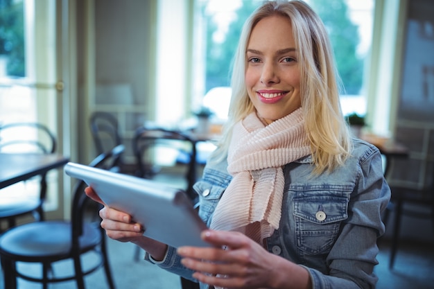 Free Photo smiling woman using digital tablet in cafe