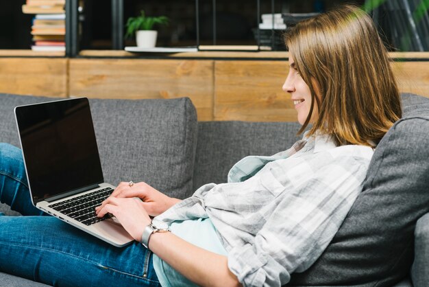 Smiling woman using laptop on sofa