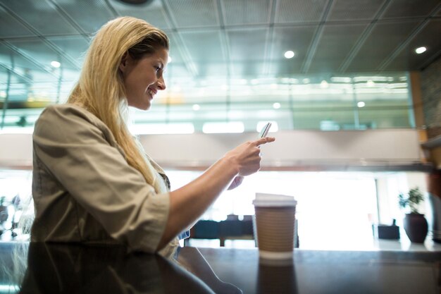 Smiling woman using mobile phone in waiting area