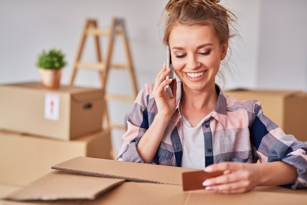 Free Photo smiling woman using phone while moving house