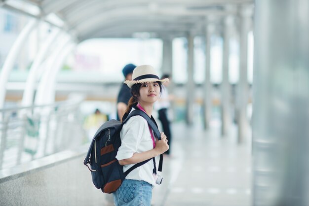 Smiling woman walking outdoors, young lady admiring city sight with walkway and buildings in background. 