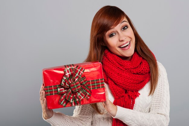 Smiling woman in warm clothes holding christmas gift