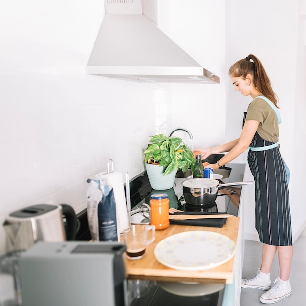 Free photo smiling woman washing red tomatoes in sink