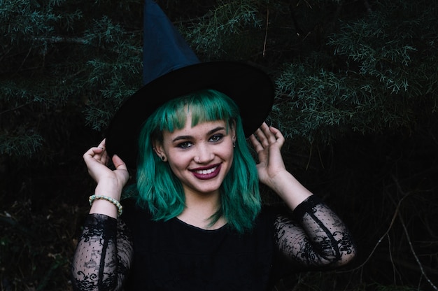 Smiling woman in witch hat in woods