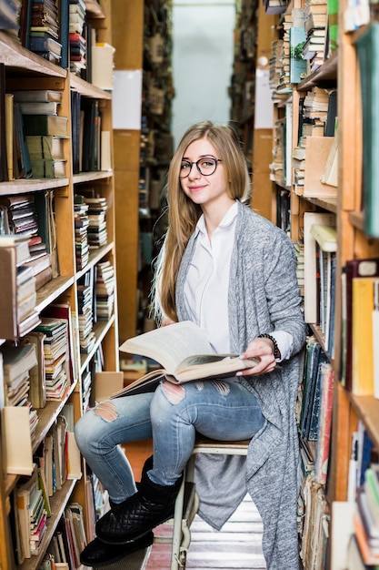 Free Photo smiling woman with book sitting on stool