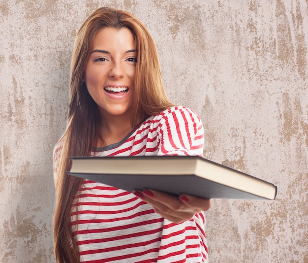 Free Photo smiling woman with book on textured wall