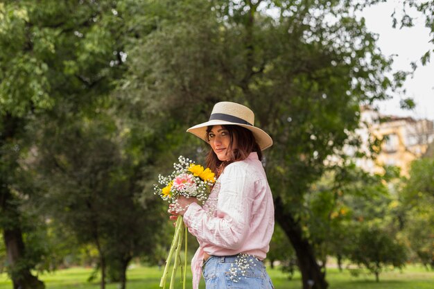 Smiling woman with bunch of flowers in park