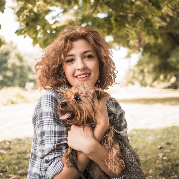 Free photo smiling woman with dog in park