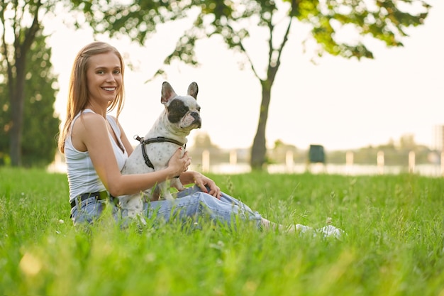 Smiling woman with french bulldog on grass