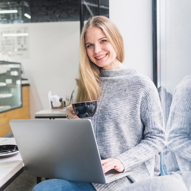 Free photo smiling woman with laptop at cafe