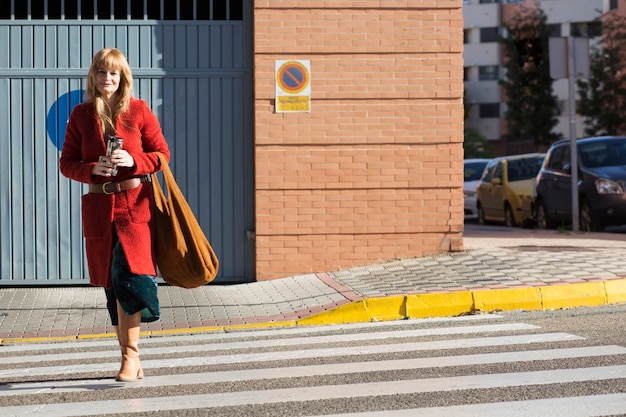 Free photo smiling woman with thermos crossing street