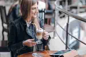 Free photo smiling woman with white headphones and a smoothie on the table