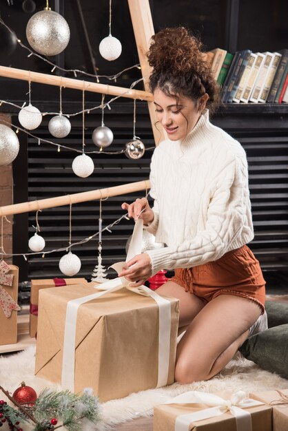 Smiling woman wrapping a big box of Christmas present