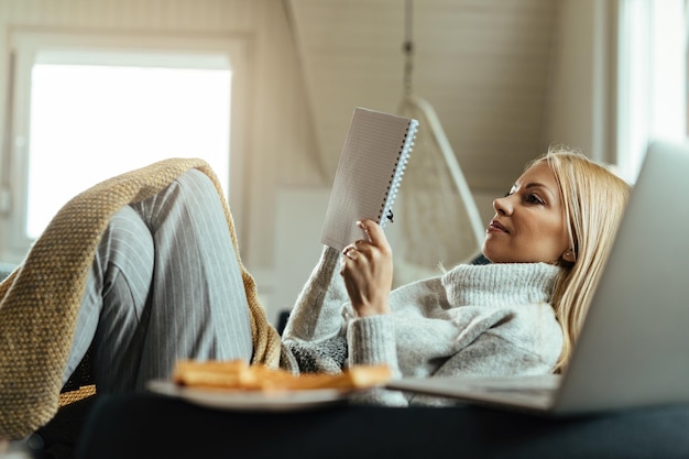 Free photo smiling woman writing in notebook while resting in the living room.