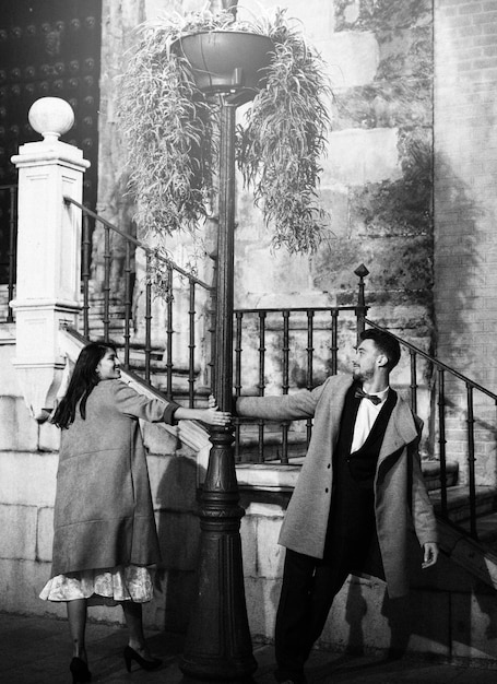 Free Photo smiling woman and young man whirling around street lamp