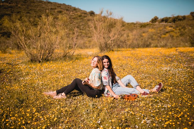 Smiling women playing ukulele in field