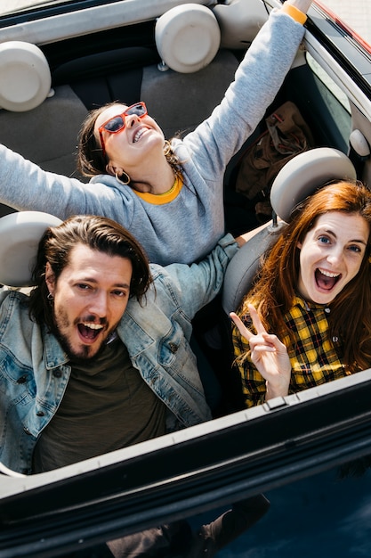 Smiling women and positive man sitting in car