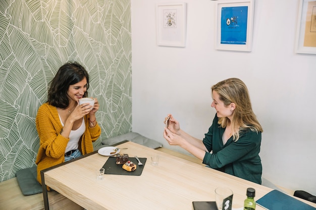 Smiling women taking photos in cafe