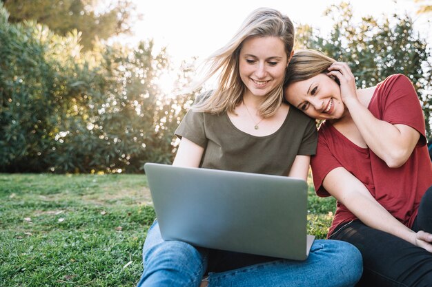 Smiling women using laptop on ground