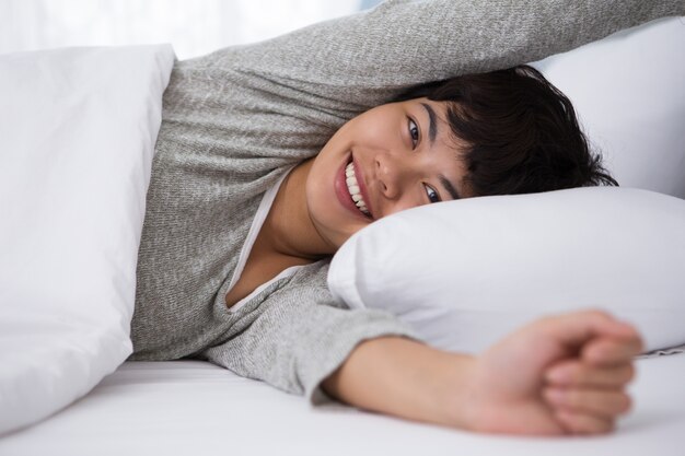 Smiling Young Asian Girl Waking up in Bed