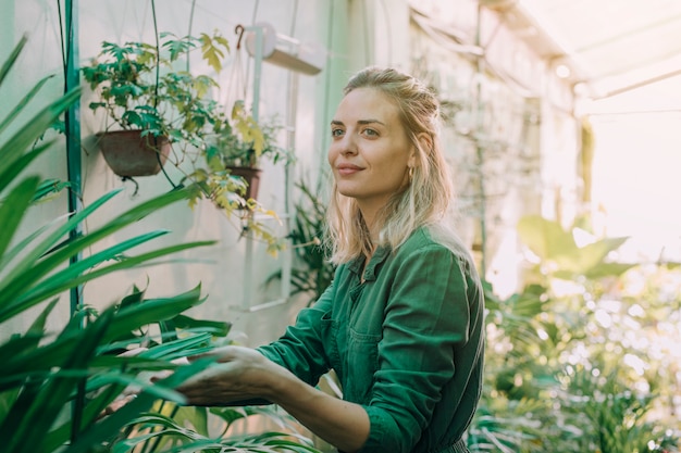 Smiling young attractive woman working at the plants nursery