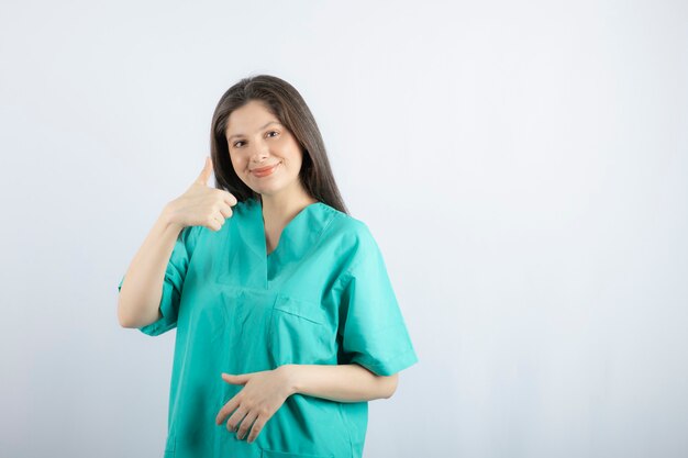 Smiling young beautiful nurse making thumb up