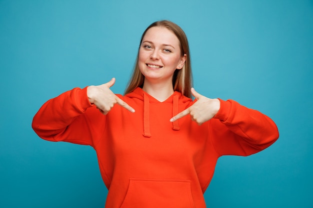 Free Photo smiling young blonde woman pointing at herself 