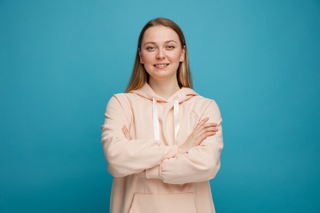 Smiling young blonde woman standing with closed posture 