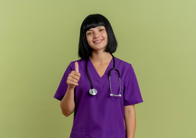 Smiling young brunette female doctor in uniform with stethoscope