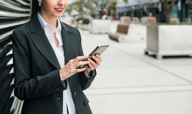 Smiling young businesswoman using smart phone