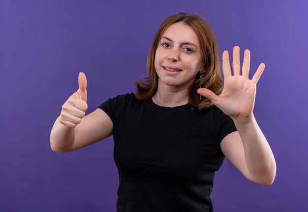 Smiling young casual woman showing six on isolated purple space